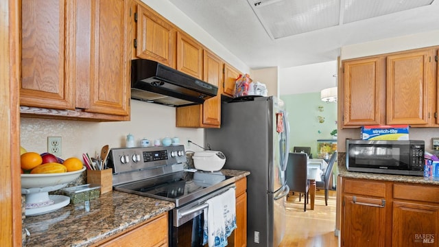 kitchen with dark stone counters, light wood-type flooring, and appliances with stainless steel finishes