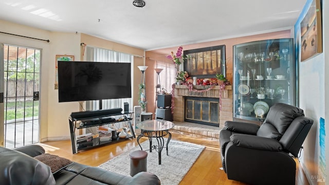 living room with light wood-type flooring and a brick fireplace