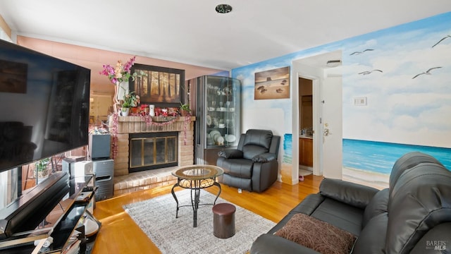 living room featuring wood-type flooring and a brick fireplace