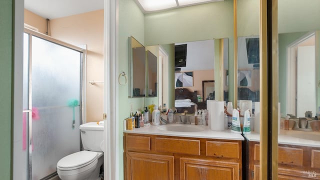 bathroom with vanity, toilet, and a shower with door