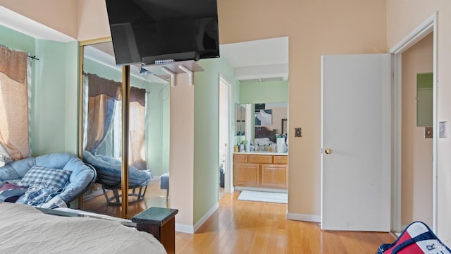 bedroom with ensuite bath and light hardwood / wood-style flooring