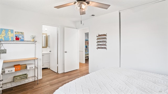 bedroom with a textured ceiling, ensuite bathroom, ceiling fan, and light hardwood / wood-style floors