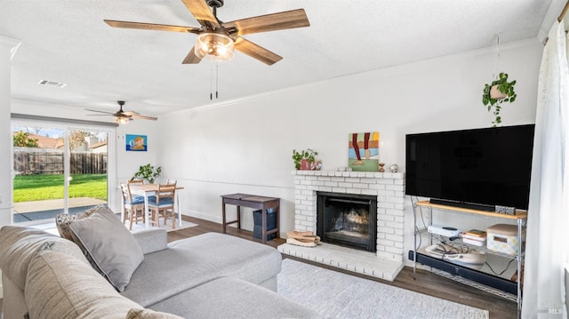 living room featuring a textured ceiling, dark hardwood / wood-style floors, a brick fireplace, and crown molding