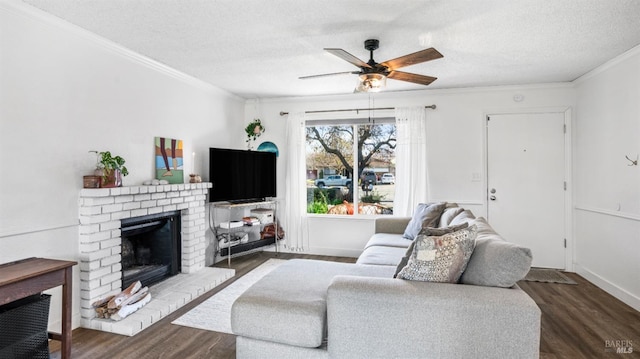 living room featuring dark hardwood / wood-style flooring, a textured ceiling, ceiling fan, crown molding, and a fireplace