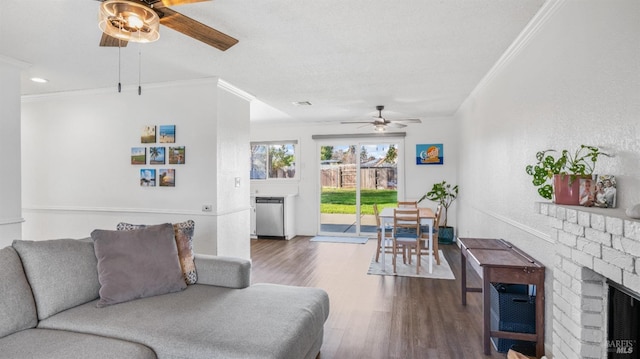 living room featuring hardwood / wood-style floors, a brick fireplace, ceiling fan, and crown molding