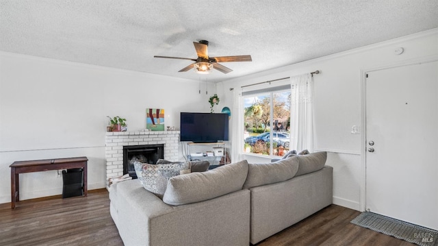 living room with dark hardwood / wood-style flooring, ornamental molding, a textured ceiling, ceiling fan, and a fireplace