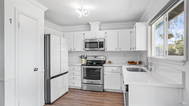 kitchen featuring white cabinetry, sink, stainless steel appliances, crown molding, and hardwood / wood-style floors