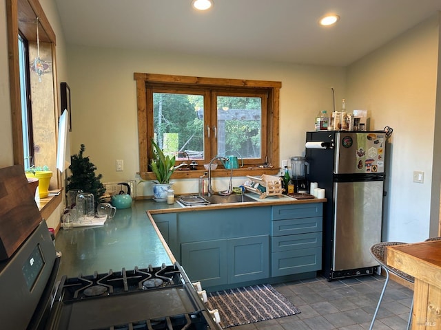 kitchen with sink, stainless steel fridge, blue cabinetry, and range with gas cooktop