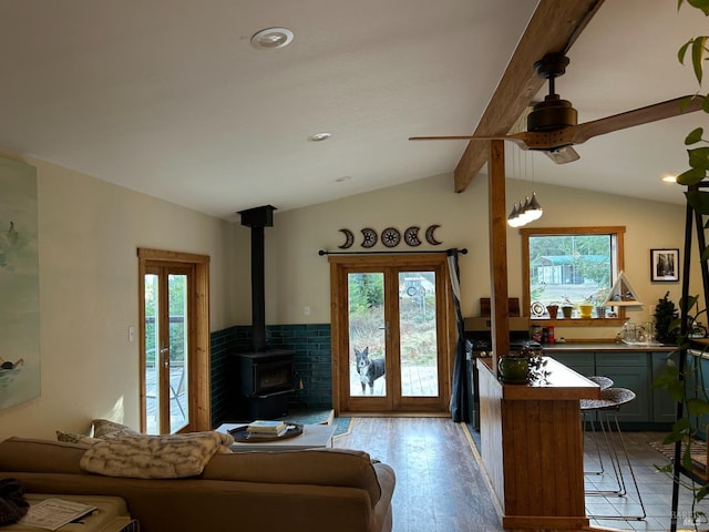 living room with light hardwood / wood-style floors, lofted ceiling with beams, a wealth of natural light, and a wood stove