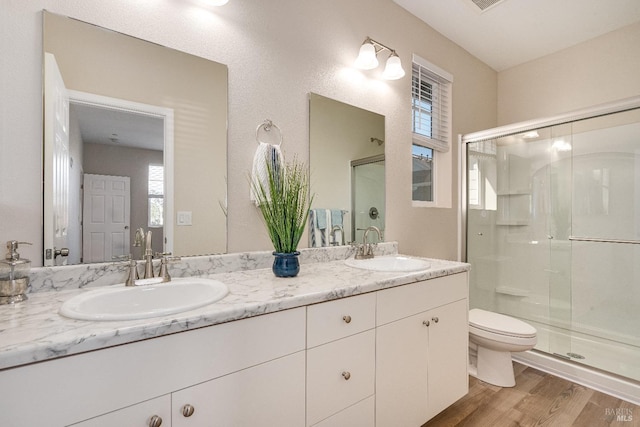 bathroom featuring vanity, hardwood / wood-style floors, a shower with door, and toilet