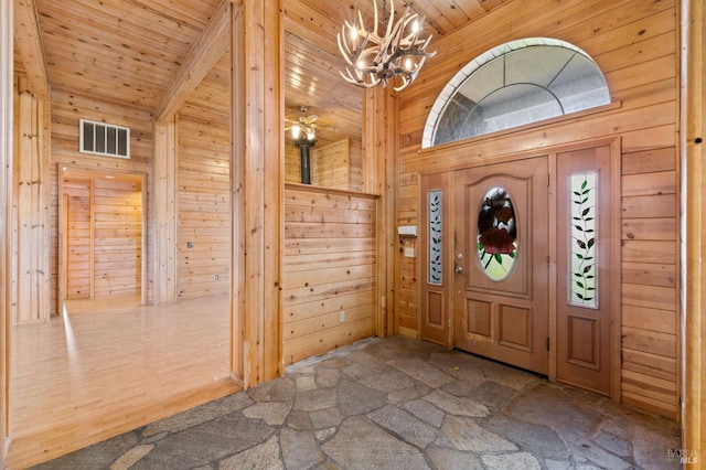 foyer with high vaulted ceiling, wooden ceiling, wooden walls, and a chandelier