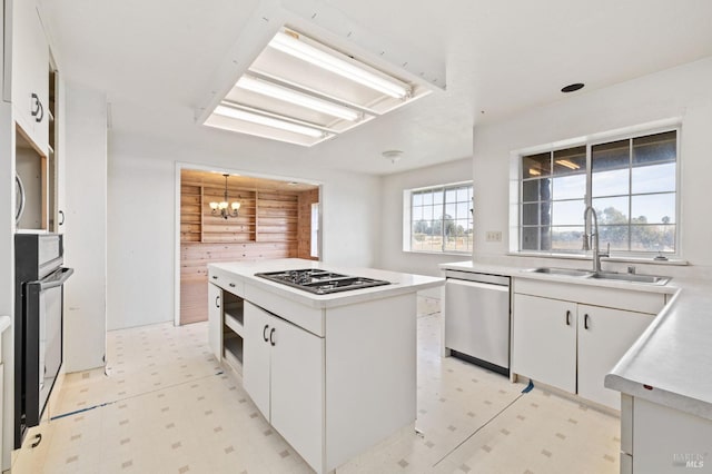 kitchen featuring white cabinets, sink, wooden walls, a kitchen island, and stainless steel appliances