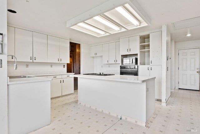 kitchen with white cabinetry, sink, a kitchen island, and oven