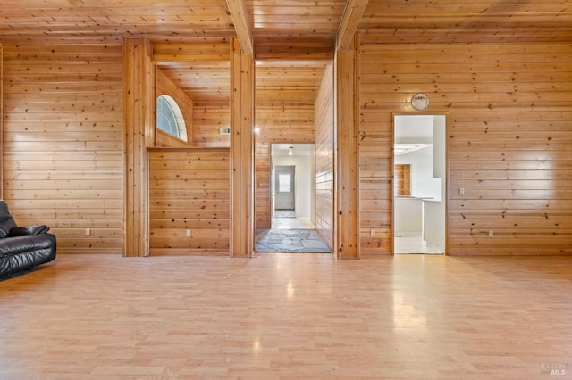 unfurnished living room with beamed ceiling, hardwood / wood-style floors, wood ceiling, and wood walls