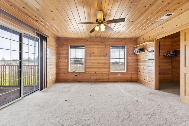 spare room with carpet, ceiling fan, wood ceiling, and wooden walls