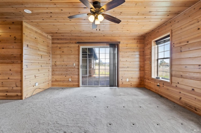 unfurnished room featuring carpet flooring, ceiling fan, wood ceiling, and wooden walls