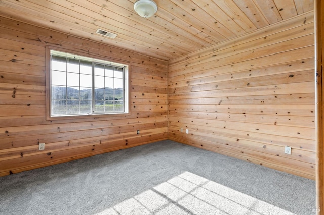 empty room with carpet, wood ceiling, and wooden walls