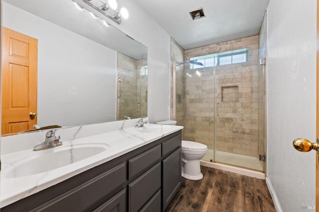 bathroom with hardwood / wood-style floors, vanity, toilet, and walk in shower