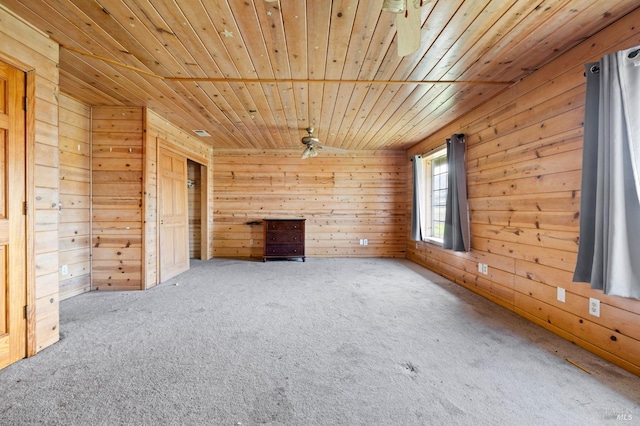 unfurnished living room with carpet floors, ceiling fan, wood walls, and wood ceiling