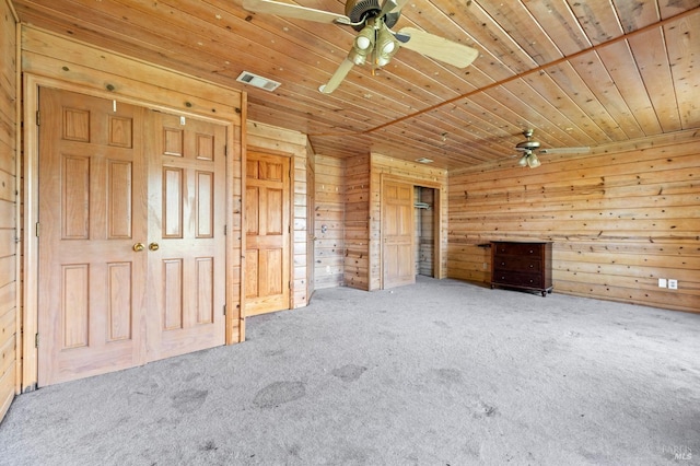 unfurnished bedroom featuring carpet flooring, wooden walls, ceiling fan, and wood ceiling