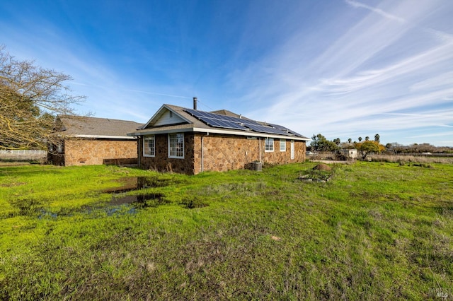 rear view of house with a lawn and solar panels