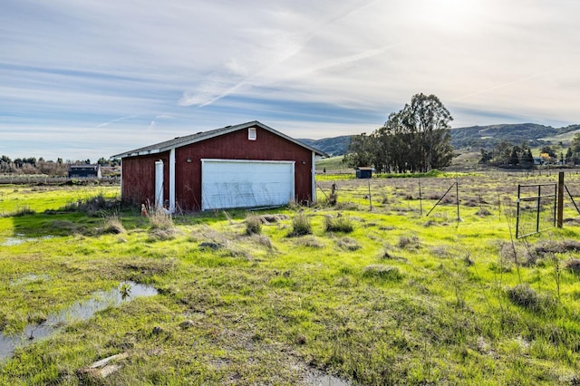 view of outbuilding featuring a mountain view, a rural view, and a garage