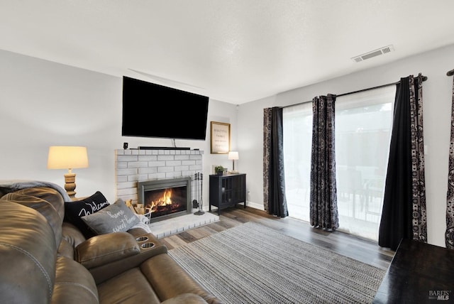 living room featuring wood-type flooring and a brick fireplace