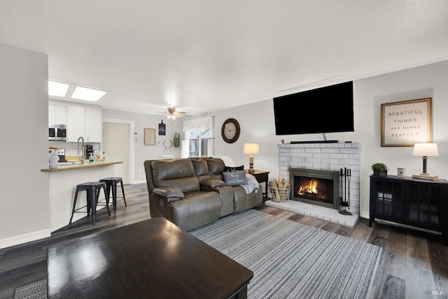 living room with ceiling fan, dark wood-type flooring, and a fireplace