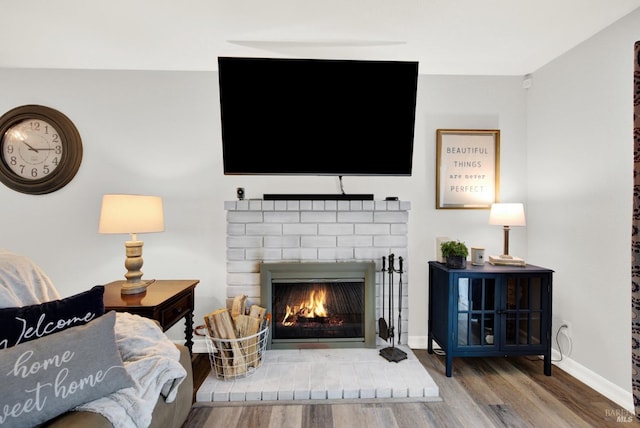 living room featuring hardwood / wood-style flooring and a brick fireplace