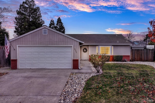 ranch-style house with a garage and a lawn