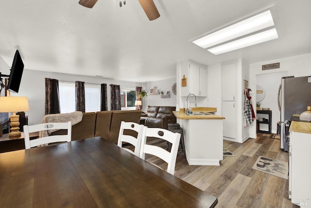 dining space with ceiling fan, sink, and light hardwood / wood-style floors