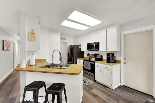 kitchen with a kitchen bar, sink, white cabinetry, kitchen peninsula, and stainless steel appliances