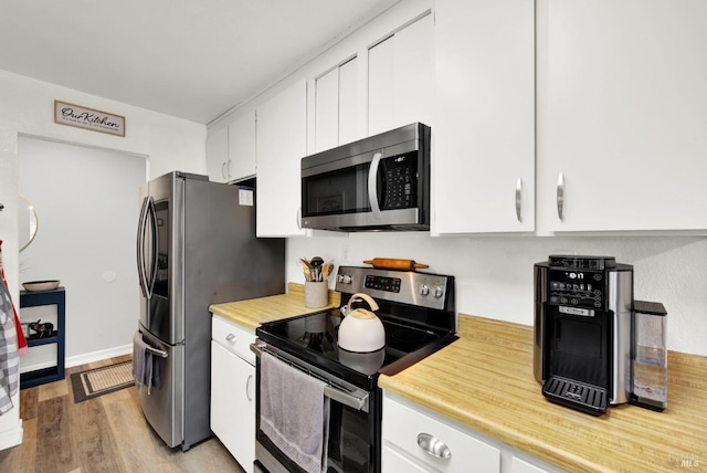 kitchen with stainless steel appliances, white cabinets, and light hardwood / wood-style floors