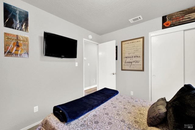 carpeted bedroom featuring a textured ceiling and a closet