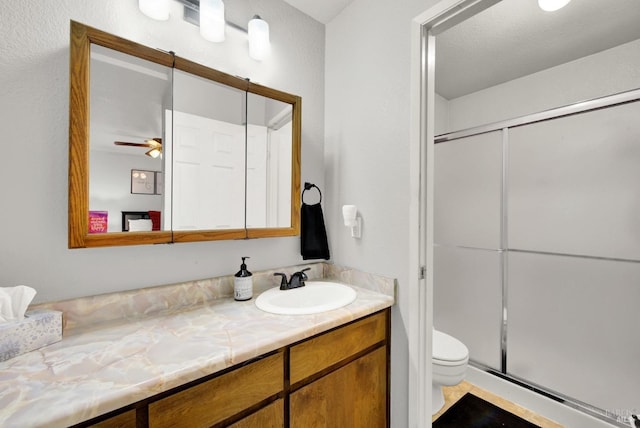 bathroom with vanity, ceiling fan, toilet, and walk in shower