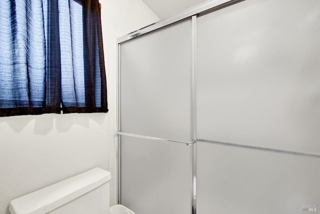 bathroom with a shower with shower door and toilet