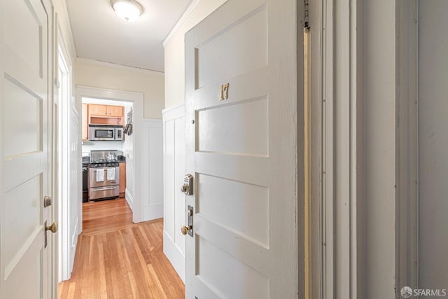 hallway with light hardwood / wood-style floors and ornamental molding