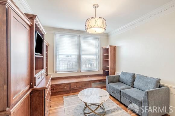 living area featuring light hardwood / wood-style floors and crown molding