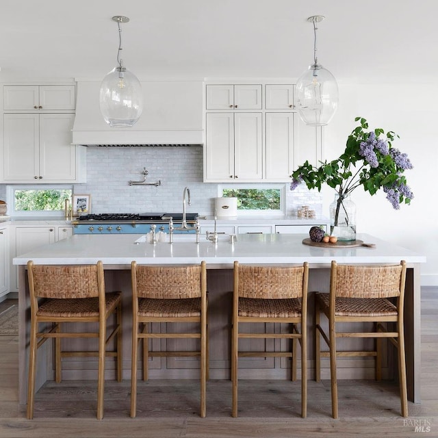 kitchen featuring tasteful backsplash, white cabinets, a breakfast bar, and an island with sink