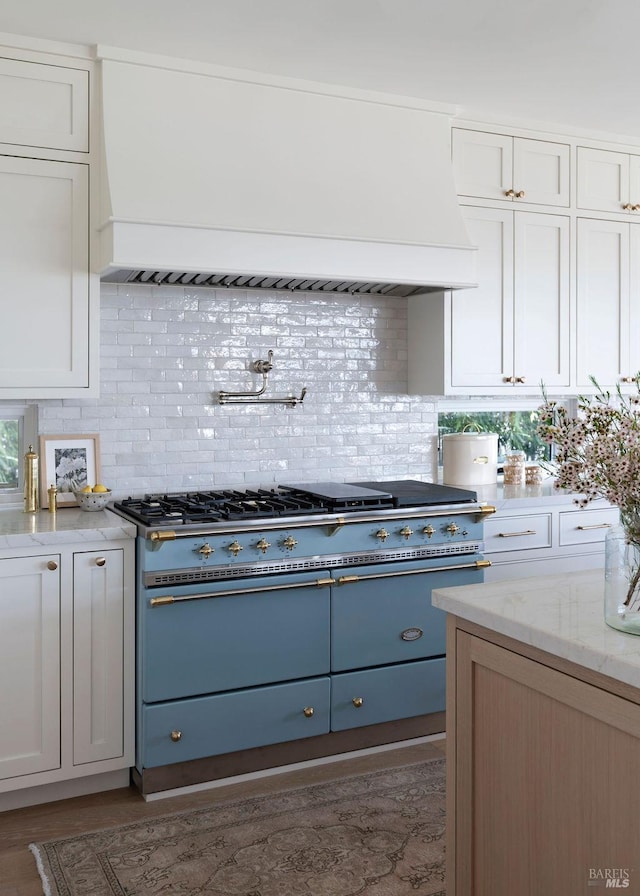 kitchen featuring backsplash, premium range hood, and white cabinetry