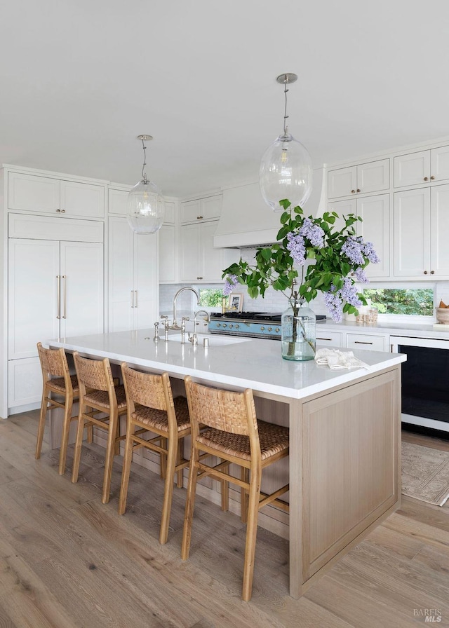 kitchen with pendant lighting, light hardwood / wood-style floors, white cabinetry, and a large island