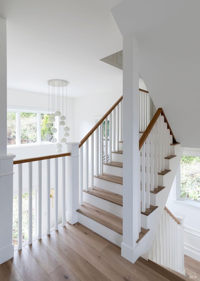 staircase with wood-type flooring and a notable chandelier