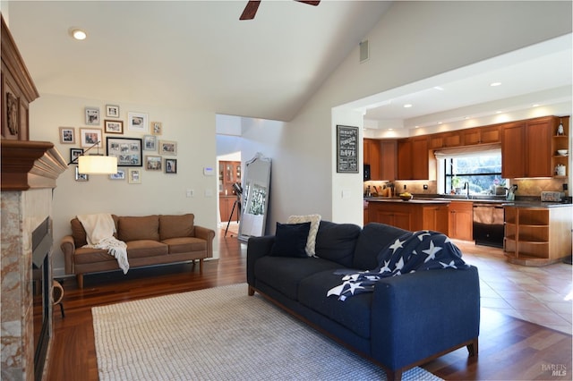 living room with a tile fireplace, wood-type flooring, ceiling fan, and lofted ceiling