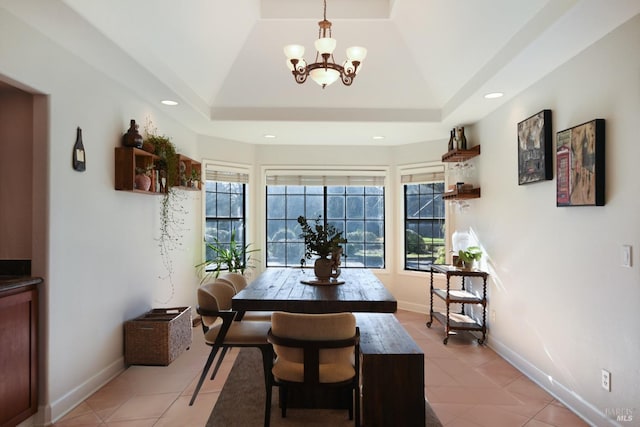 tiled dining area with a chandelier, vaulted ceiling, a raised ceiling, and a healthy amount of sunlight