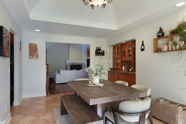 tiled dining area with a tray ceiling