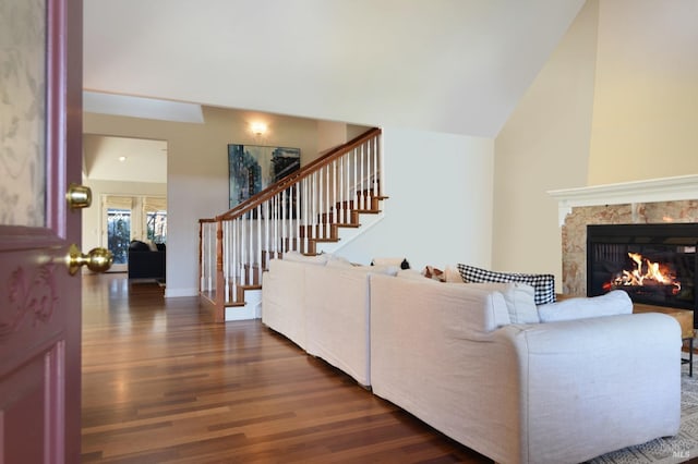 living room with a fireplace, lofted ceiling, and dark wood-type flooring