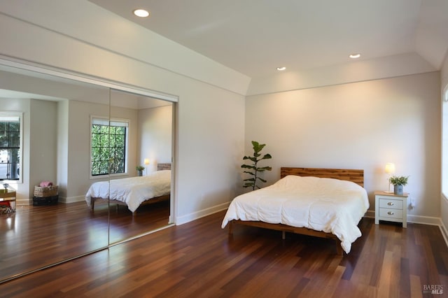 bedroom featuring a closet, dark wood-type flooring, and vaulted ceiling