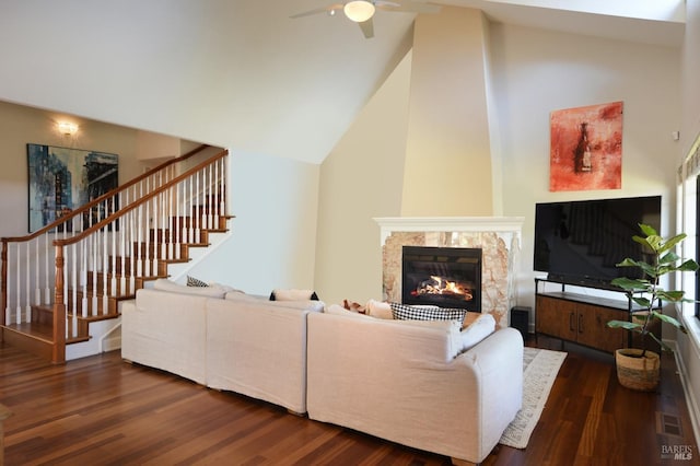 living room with ceiling fan, a high end fireplace, dark hardwood / wood-style floors, and high vaulted ceiling