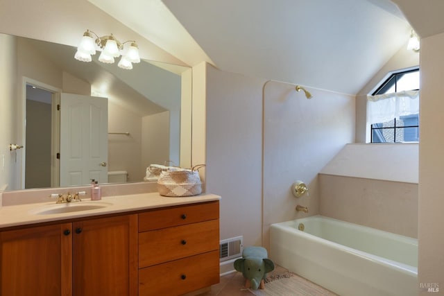 bathroom featuring a washtub, vanity, vaulted ceiling, tile patterned flooring, and toilet