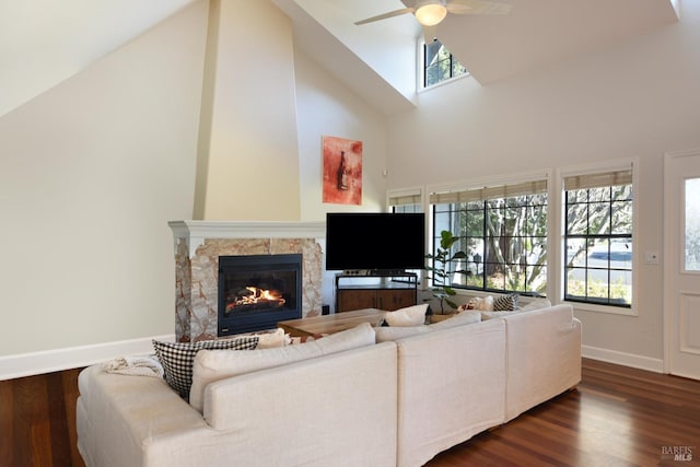 living room with ceiling fan, dark hardwood / wood-style floors, a fireplace, and high vaulted ceiling